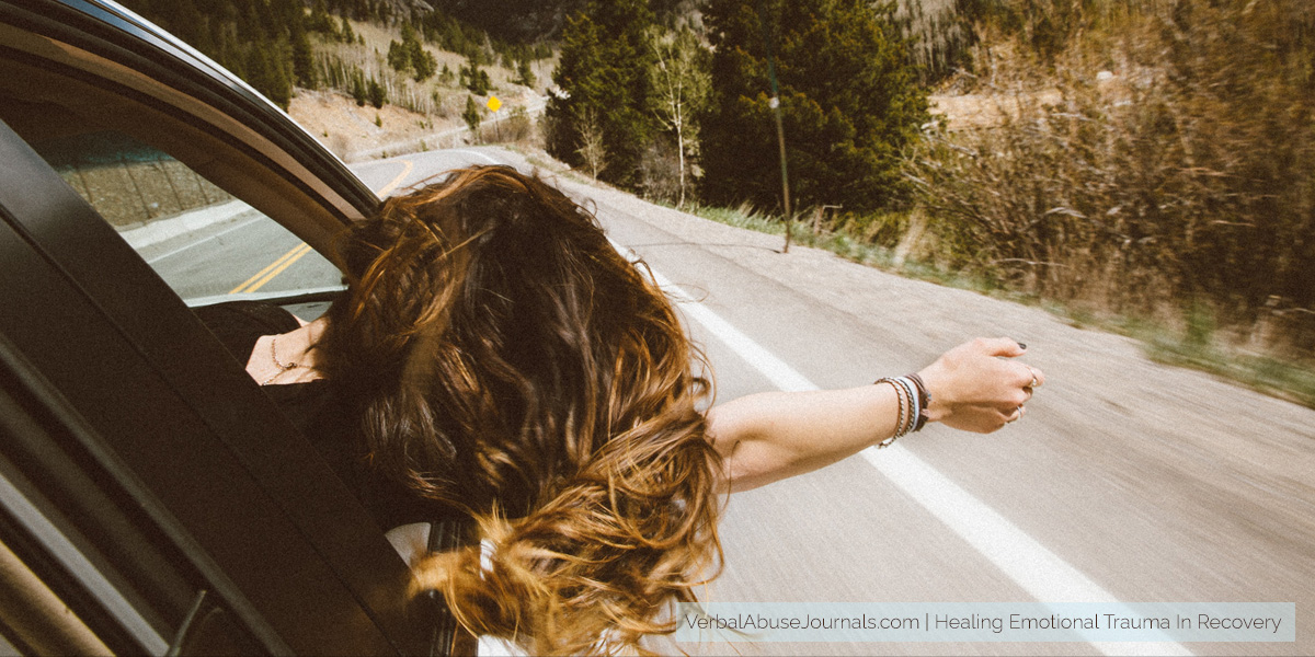 A woman in the passenger seat of a car with her head and arm outside the window, assumably in the process of healing emotional trauma