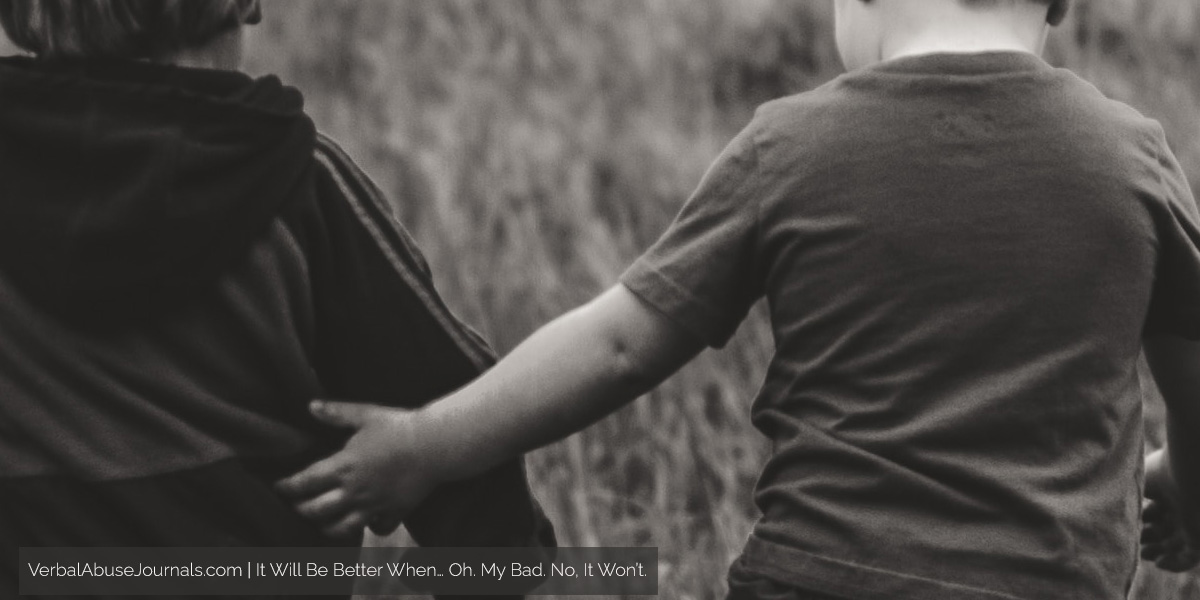 Two little boys walking through a field, one with his arm around the other.